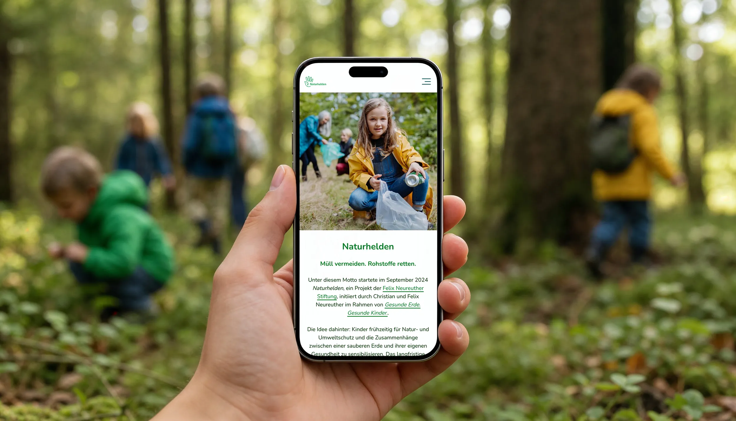 Naturhelden-Website auf einem Smartphone vor einer Gruppe von Kindern im Wald